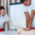 CPR class with instructors talking and demonstrating firt aid, compressions ans reanimation procedure. Cpr dummy on the table.