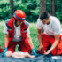 Cpr practice of woman and man on cpr baby dummy outdoors